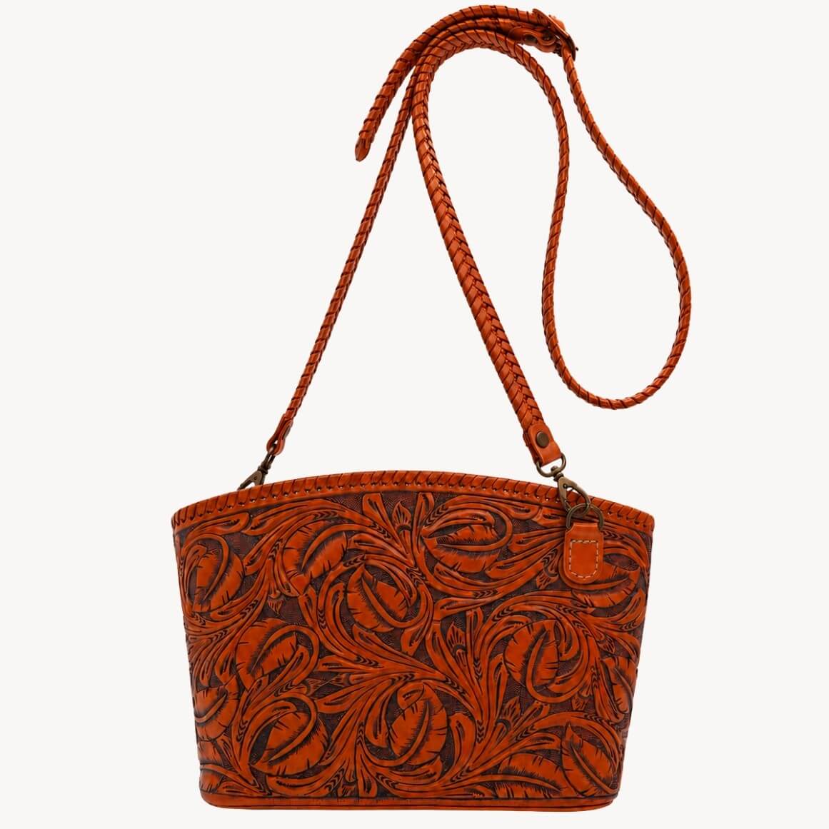Burnt orange hand-tooled leather shoulder bag with floral detailing, braided strap, and metal clasps.