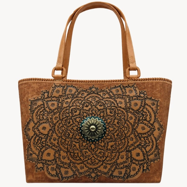 Cognac/burnished brown nude color tooled leather tote with floral mandala tooling, double shoulder straps, and antique sunburst medallion hardware on a white background.