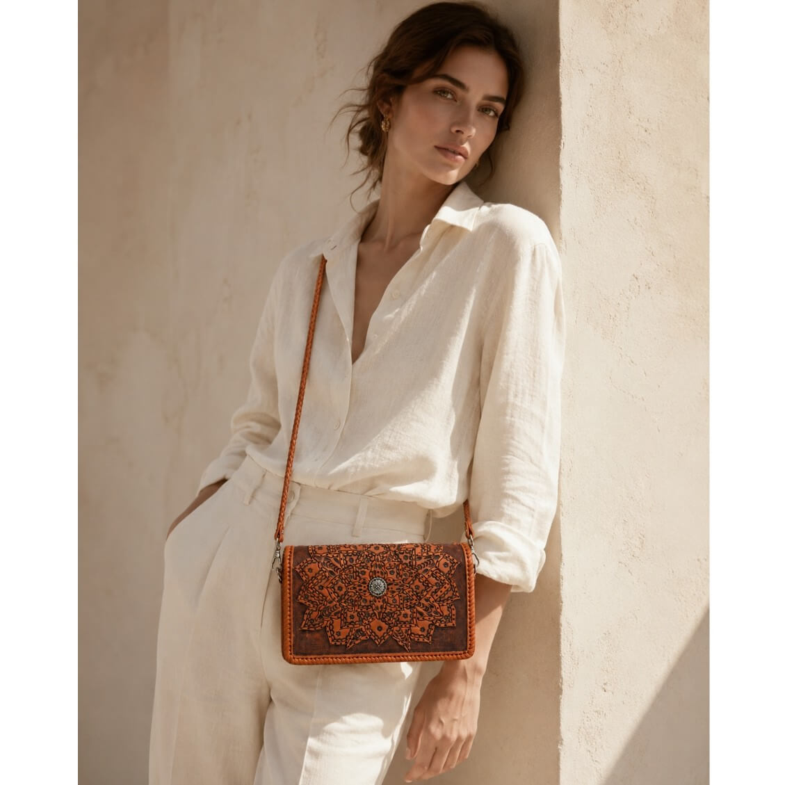 Woman carrying a handcrafted full-grain leather crossbody wallet with intricate floral mandala tooling and braided leather strap