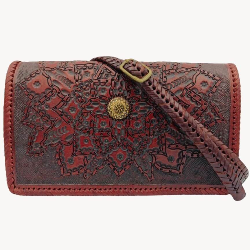 Brown leather wallet with intricate patterns and a strap on a white background