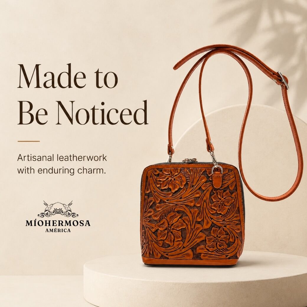 Burnt orange hand-tooled floral leather crossbody bag with long strap displayed on a cream pedestal with Made to Be Noticed headline and Miohermosa logo.