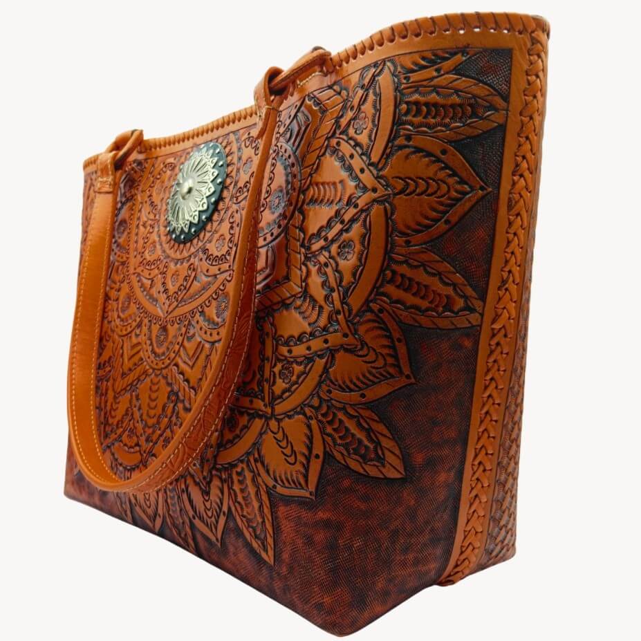 Three‑quarter view of tooled leather purse with marigold mandala and antique‑silver concho.