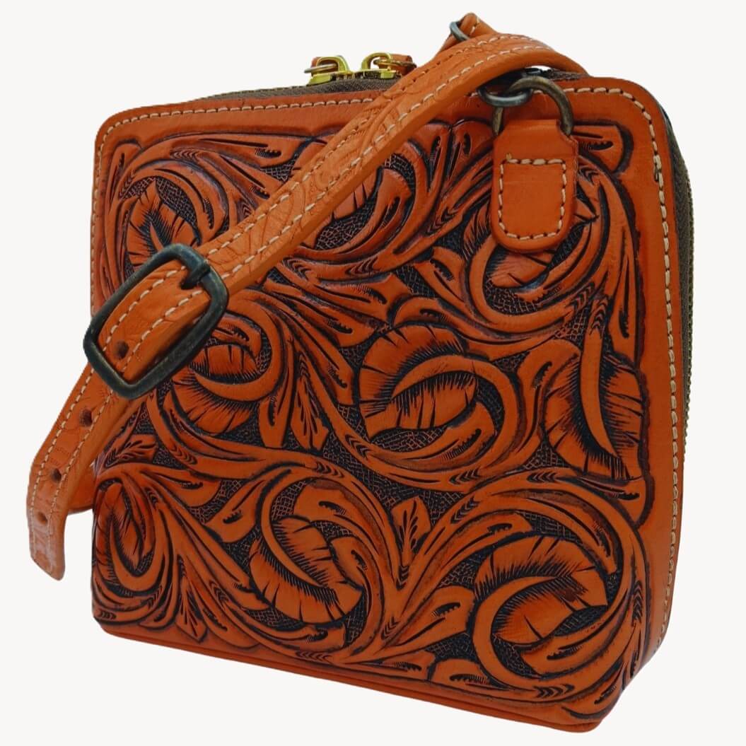 Adjustable removable crossbody strap attached to hand‑tooled leather bag