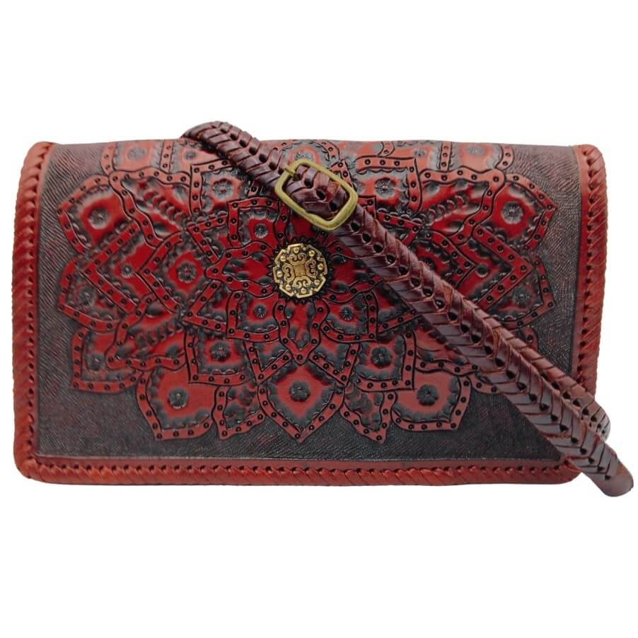 Crossbody strap attached—hand‑braided look with brass buckle on tooled mandala flap.