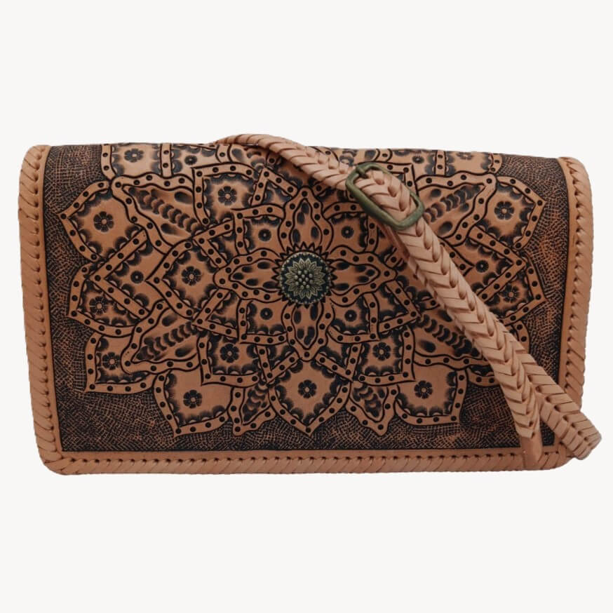 Front view with braided adjustable strap draped across the mandala tooled leather bag.