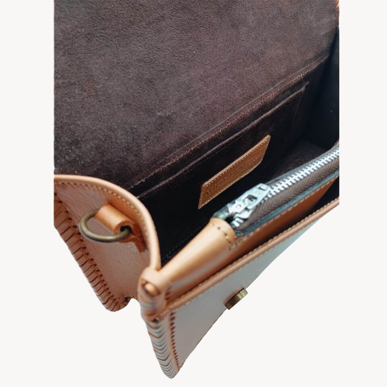 Interior view of suede‑lined crossbody with zipper pocket and slip pocket.