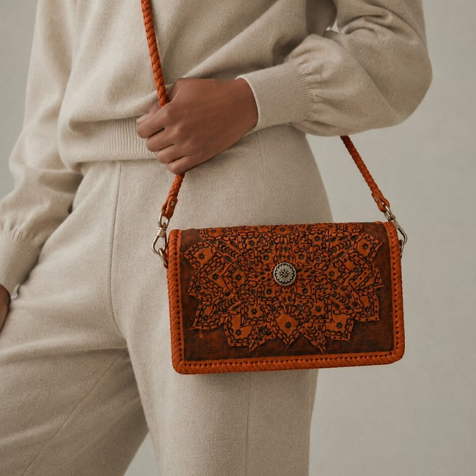 Model carrying a handcrafted brown full-grain leather crossbody wallet with an intricate floral mandala pattern