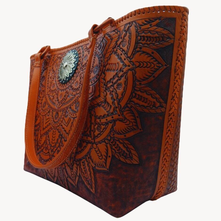 Three‑quarter view of tooled leather purse with marigold mandala and antique‑silver concho.