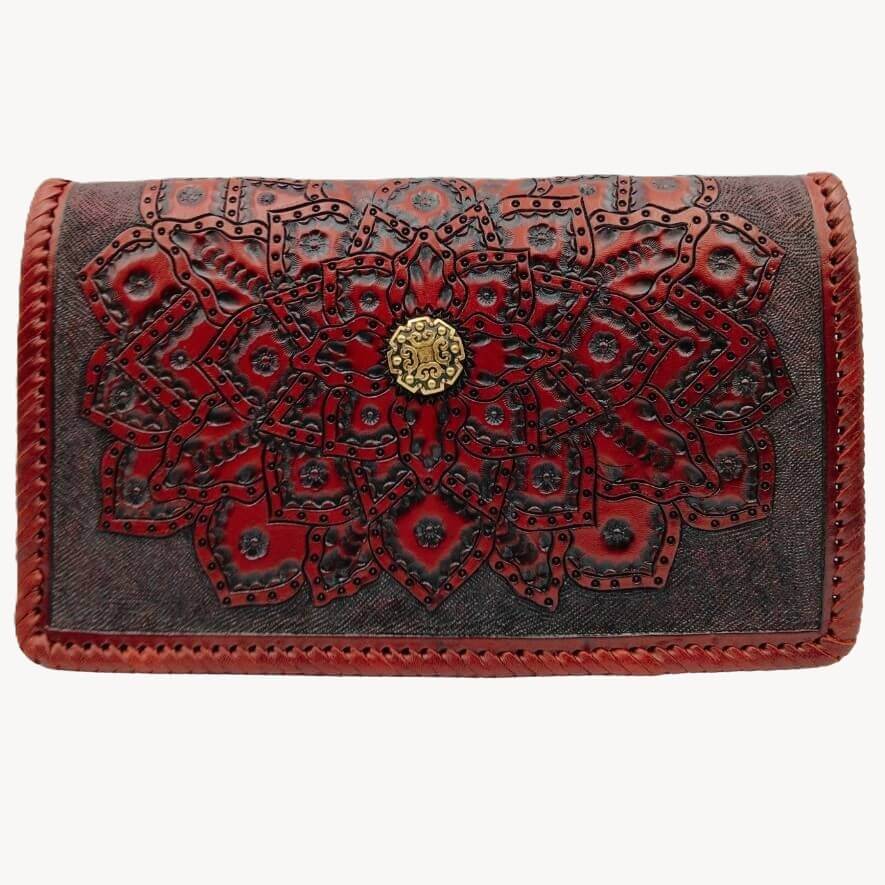 Front view of hand‑tooled full‑grain leather crossbody with embossed mandala and brass concho in deep crimson.