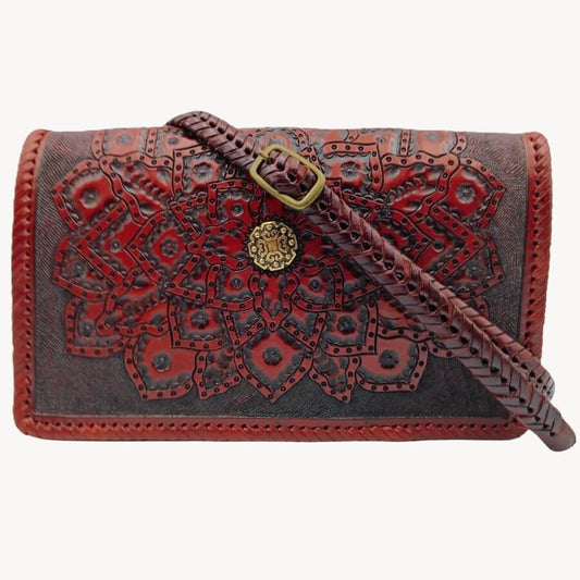 Crossbody strap attached—hand‑braided look with brass buckle on tooled mandala flap.