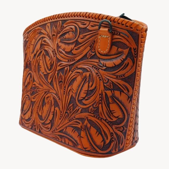 Angled view—hand‑tooled leather crossbody with removable strap tab—Miohermosa