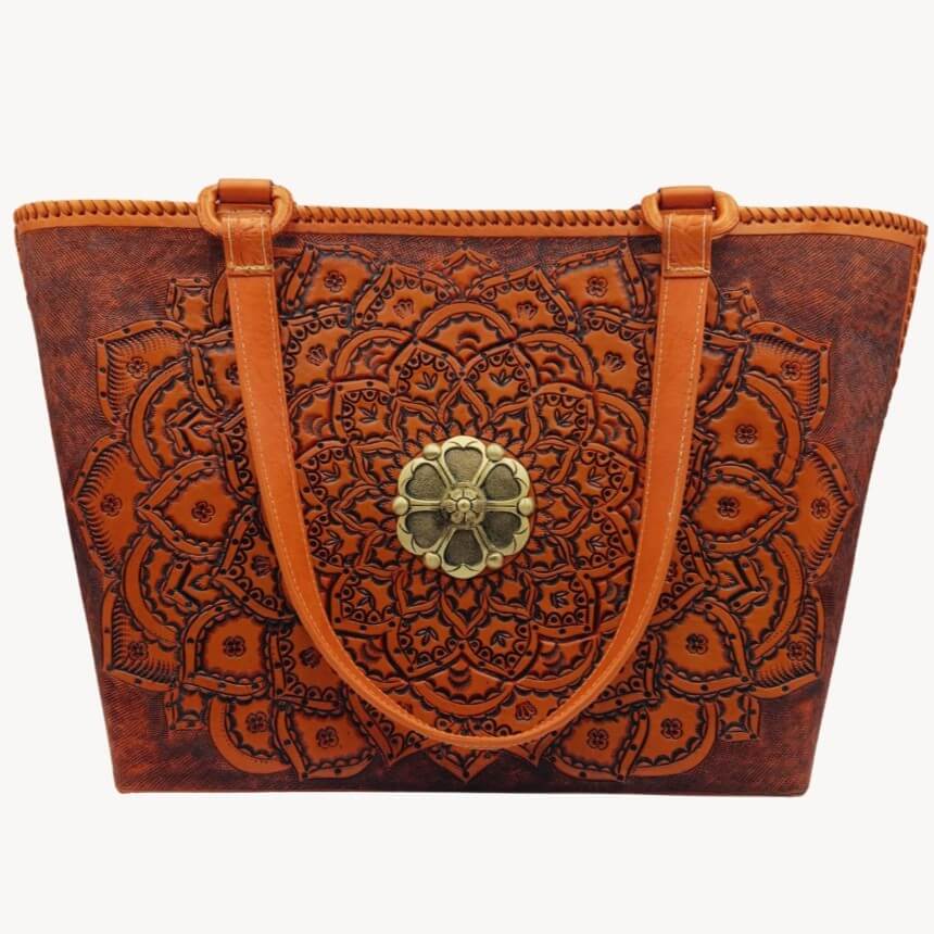Full‑grain leather tote with embossed mandala and brass medallion, front view.