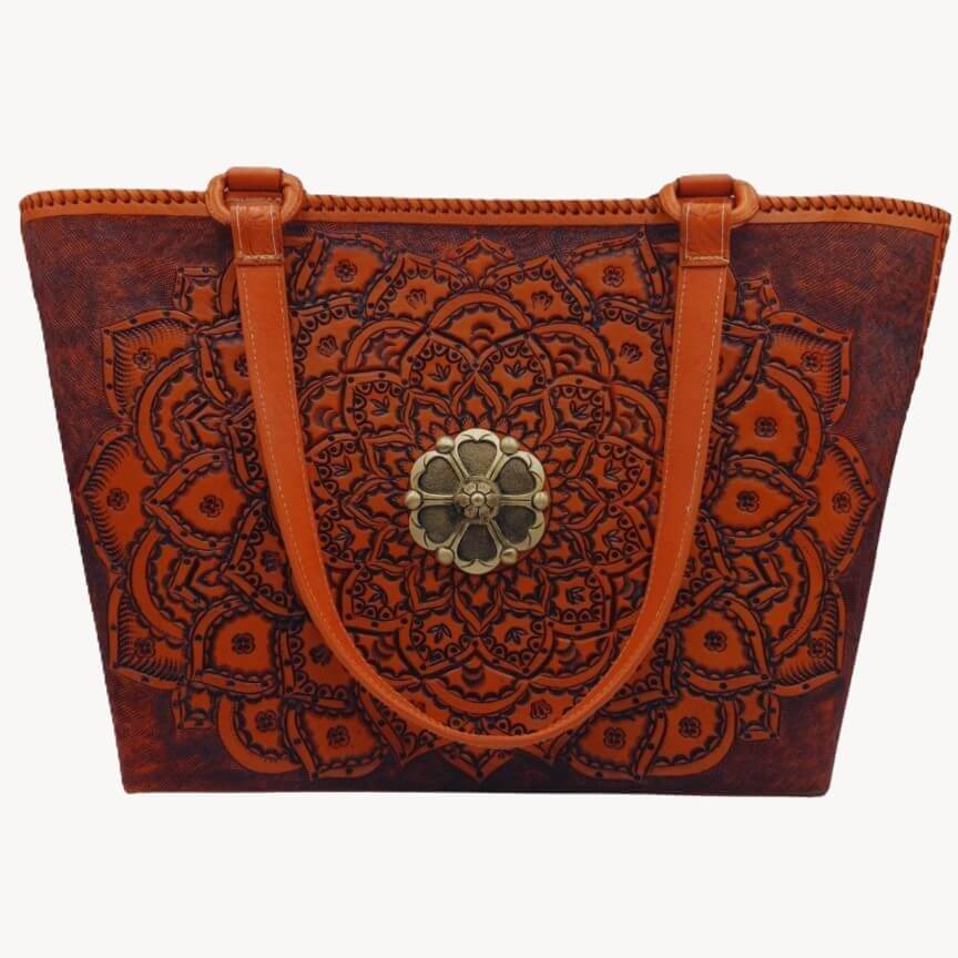 Full‑grain leather tote with embossed mandala and brass medallion, front view.