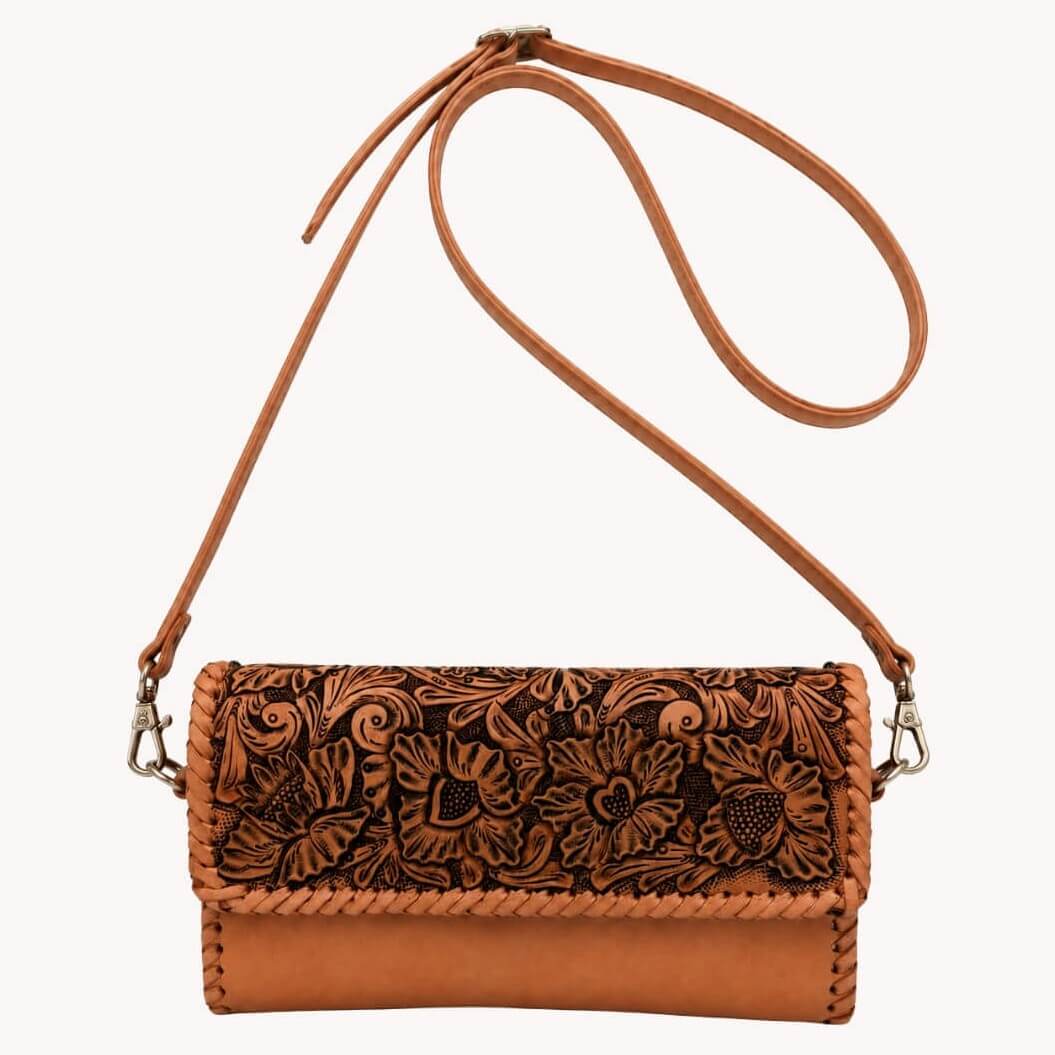 Natural tan hand-tooled leather crossbody bag with floral detailing, braided trim, adjustable shoulder strap, and metal clasps.